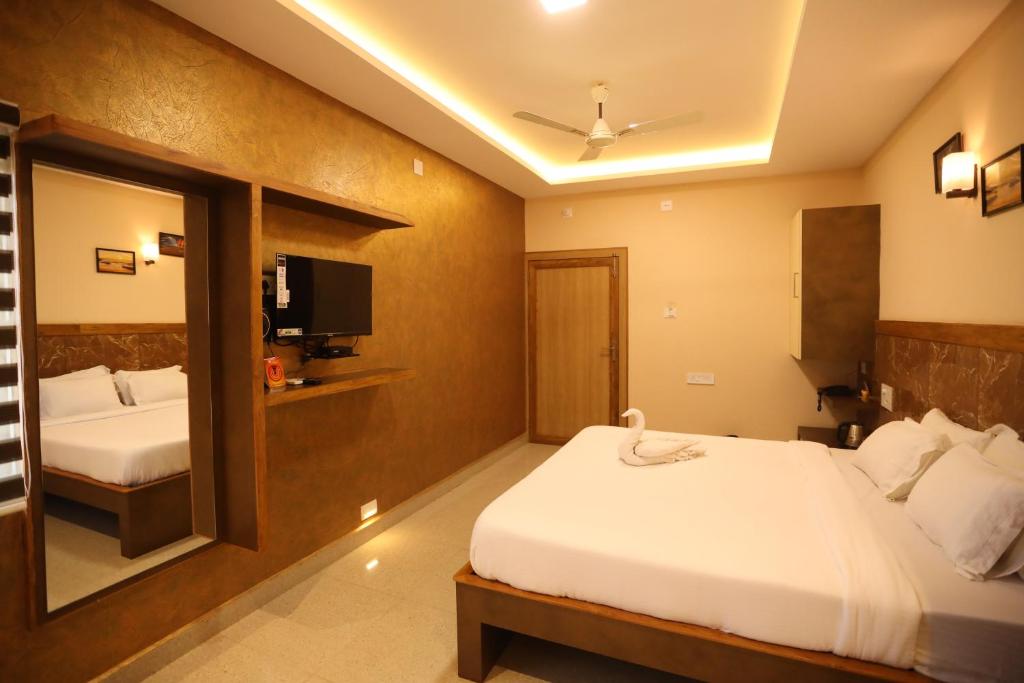a hotel room with two beds and a tv at HOTEL SOUTHERN HERITAGE in Udupi