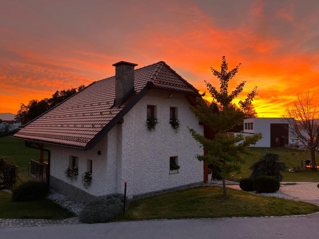 a white house with a sunset in the background at Holiday Home Dobrotin in Vojnik