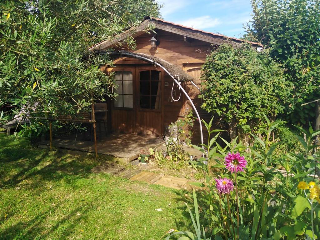 una pequeña casa de madera en un jardín con flores en Le chalet du Jardin caché, en Marmande