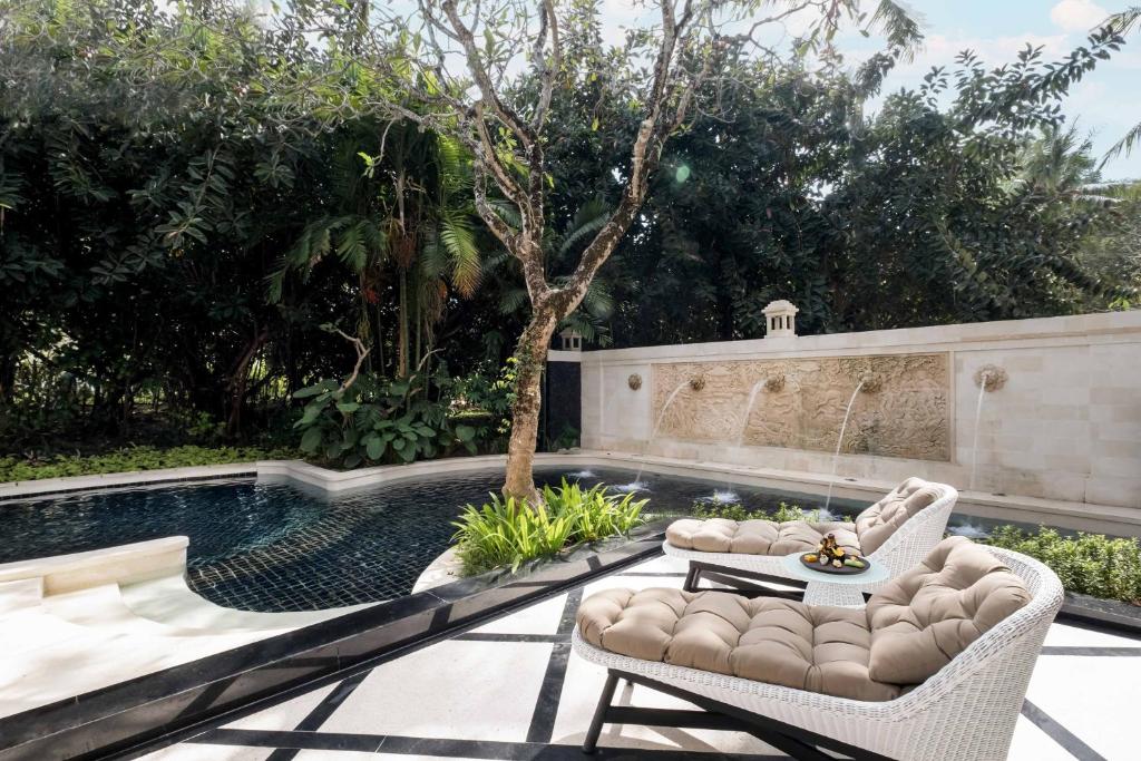 a patio with two chairs and a swimming pool at InterContinental Bali Resort by IHG in Jimbaran