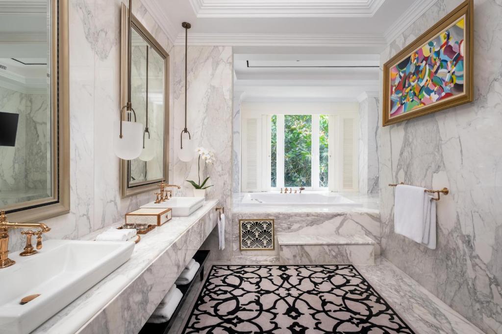 a white bathroom with two sinks and a tub and a tubermott at InterContinental Bali Resort by IHG in Jimbaran