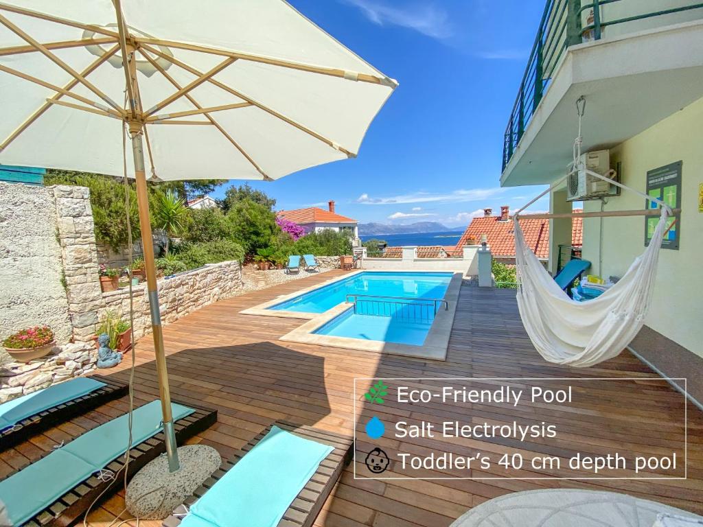 um pátio com uma rede de descanso e uma piscina em Eco Sunshine Apartments Lumbarda em Lumbarda