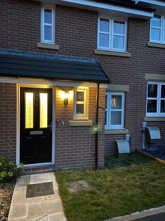 a brick house with a black door and a bench at Modern 2 bed nestled in the Abergavenny hills in Abergavenny