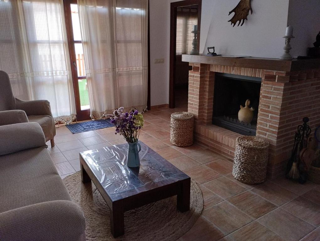 a living room with a fireplace and a table with flowers at casa rural el Realengo in Las Casas