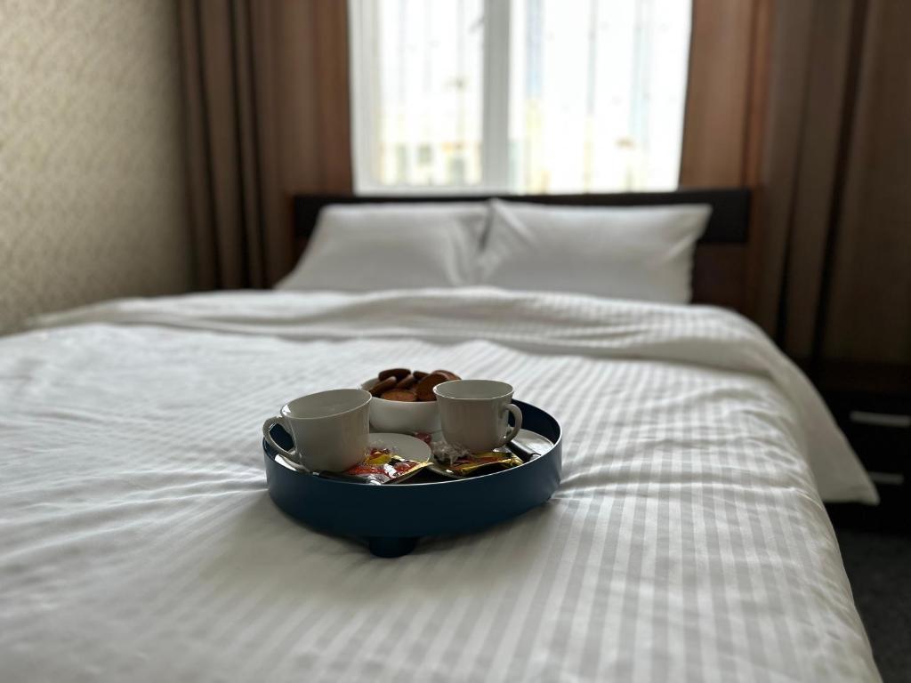 een dienblad met twee kopjes en een donut op een bed bij Апартаменты Миллениум 2 in Astana