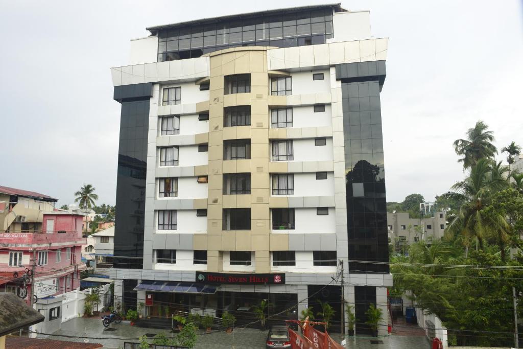 un alto edificio bianco in una città con palme di Hotel Seven Hills a Trivandrum