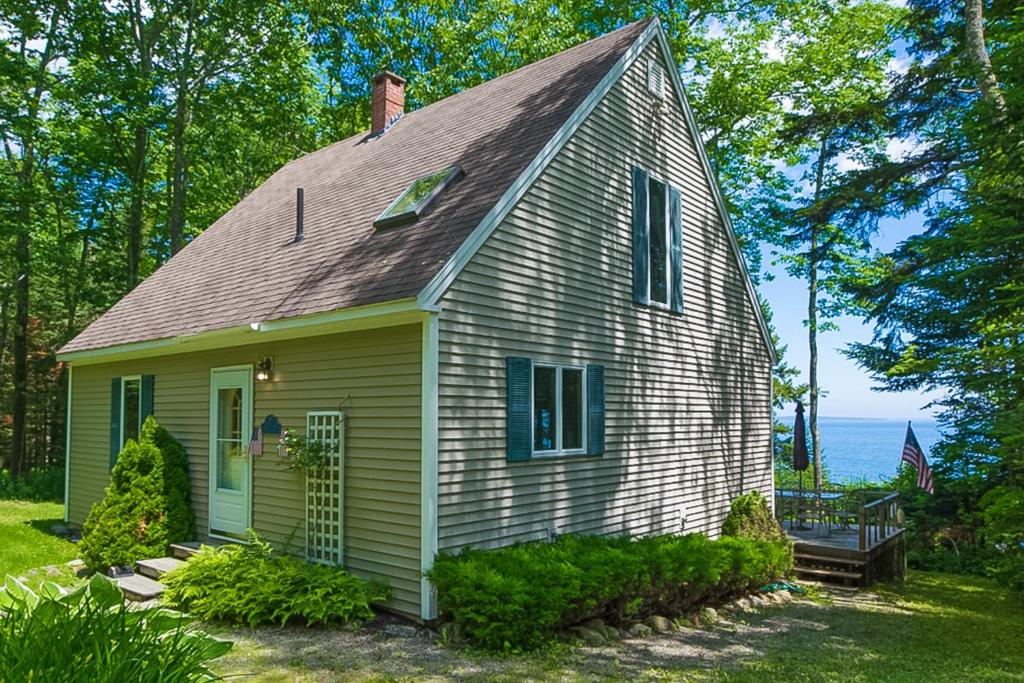 a green and white house with a roof at Serenity Cove Cottage in Camden