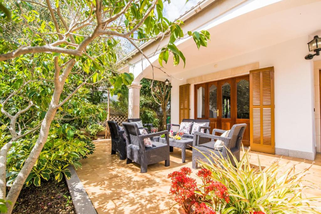 eine Terrasse mit Stühlen, einem Tisch und Bäumen in der Unterkunft Ideal Property Mallorca - Sa Dalia in Port d'Alcúdia