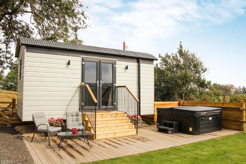 a tiny house with a deck and a grill at Cwm Cariad in Knighton