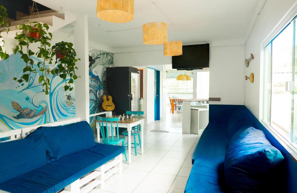 a living room with a blue couch and a kitchen at Sea Wolf Surf Hostel in Florianópolis