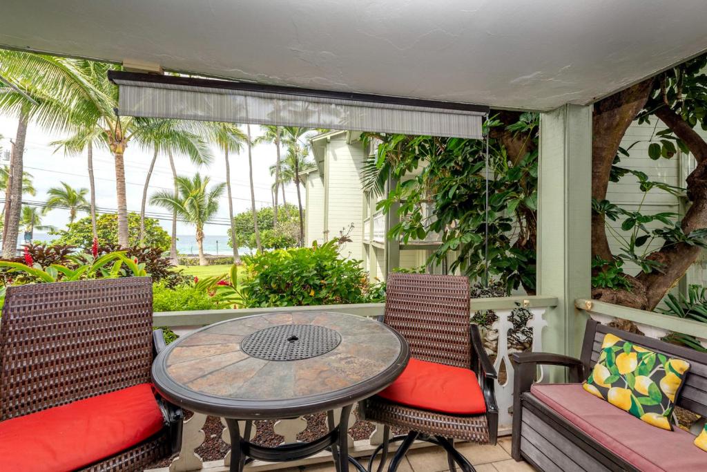 eine Veranda mit einem Tisch, Stühlen und Palmen in der Unterkunft Kona Islander Inn 147 Tropical Oasis in Kailua-Kona