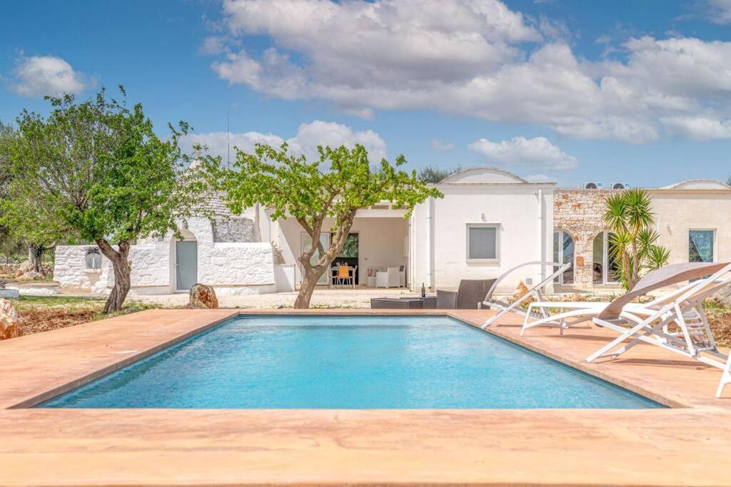 una piscina con 2 sillas y una casa en Bianco Trullo by Raro Villas, en Latiano