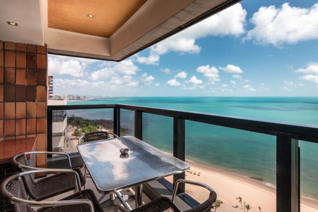 a balcony with a table and chairs and the ocean at Particular Iracema Residence in Água Boa