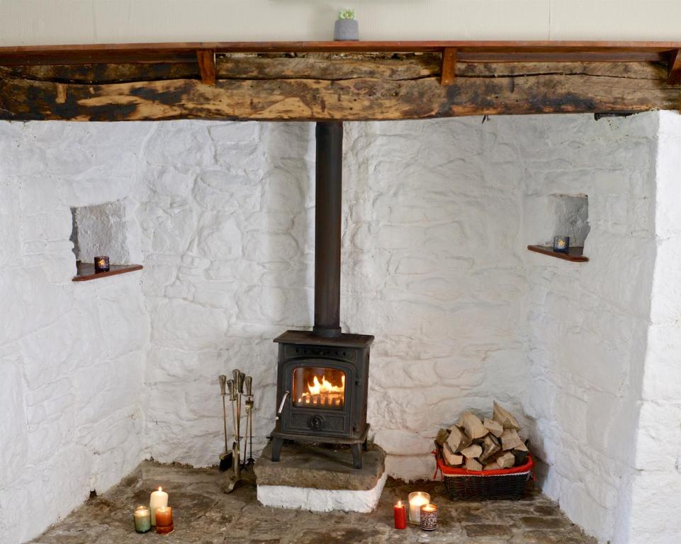 a fireplace in a stone wall with candles on the floor at Corderry Farmhouse, idyllic cottage amid 250 acres in Stagdale Bridge