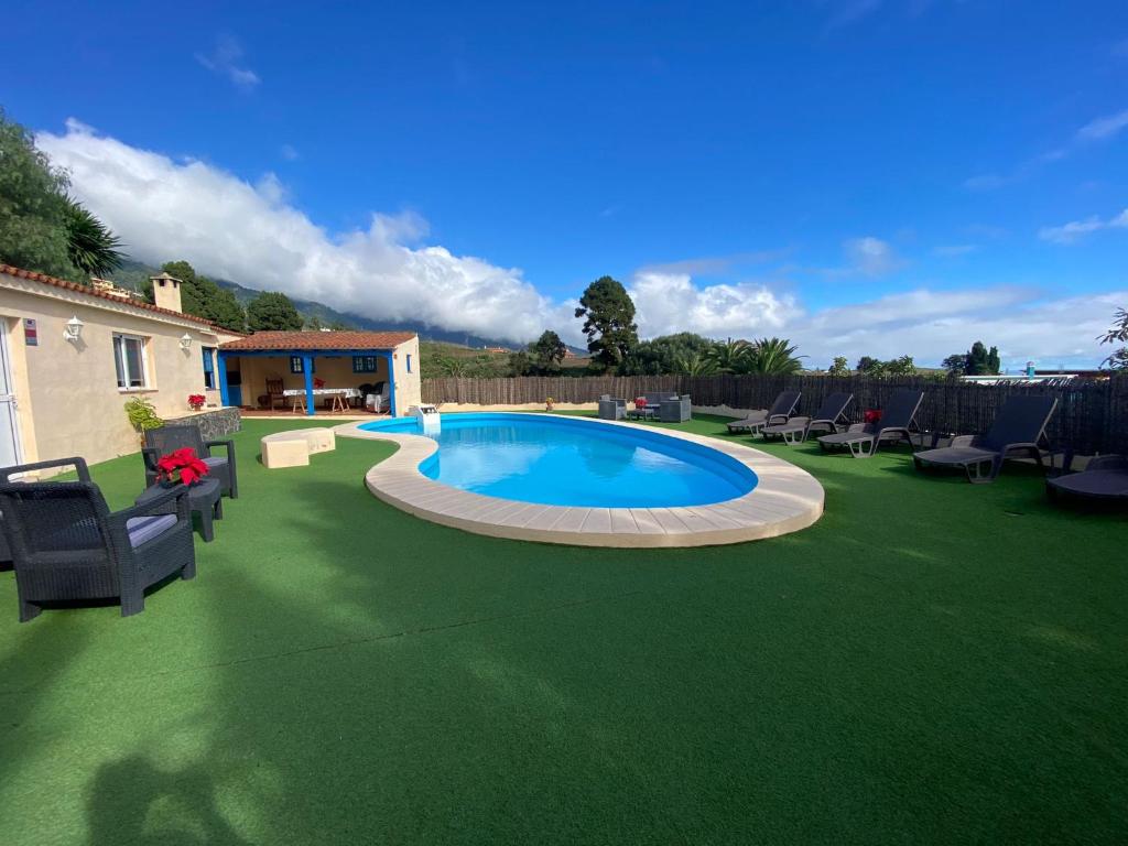 una piscina en un césped verde con sillas en Galguen Paradise in the island of stars. Villa. en Breña Alta