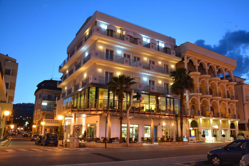 a tall white building with palm trees in front of it at Hotel La Sirenetta in Tortoreto Lido