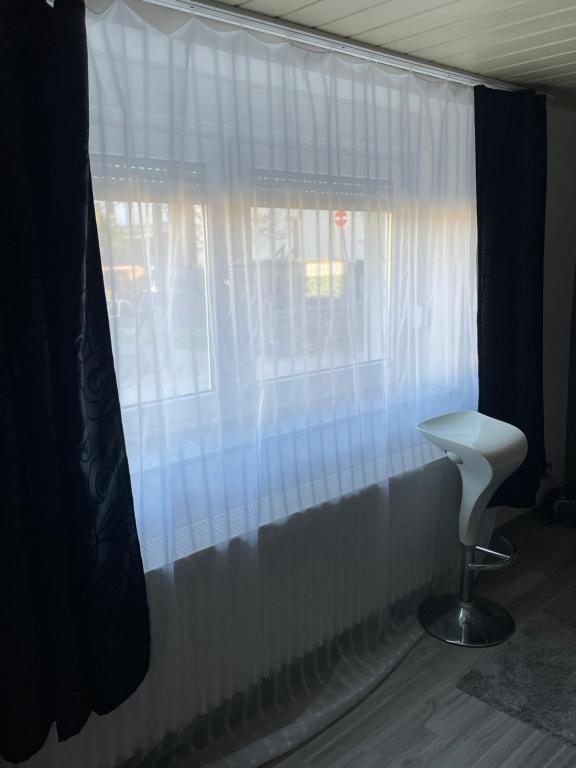 ein Fenster mit Vorhängen und einem weißen Stuhl in einem Zimmer in der Unterkunft Cocos Tiberiu in Mogendorf