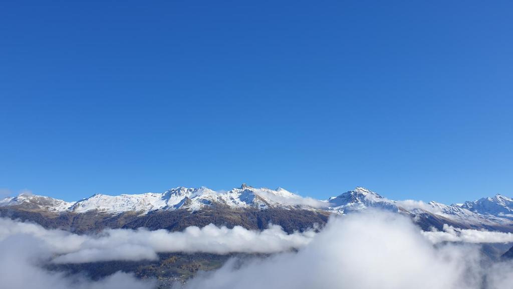 una vista de las montañas cubiertas de nieve desde arriba de las nubes en Immeuble Les Sérandes, en Les Collons