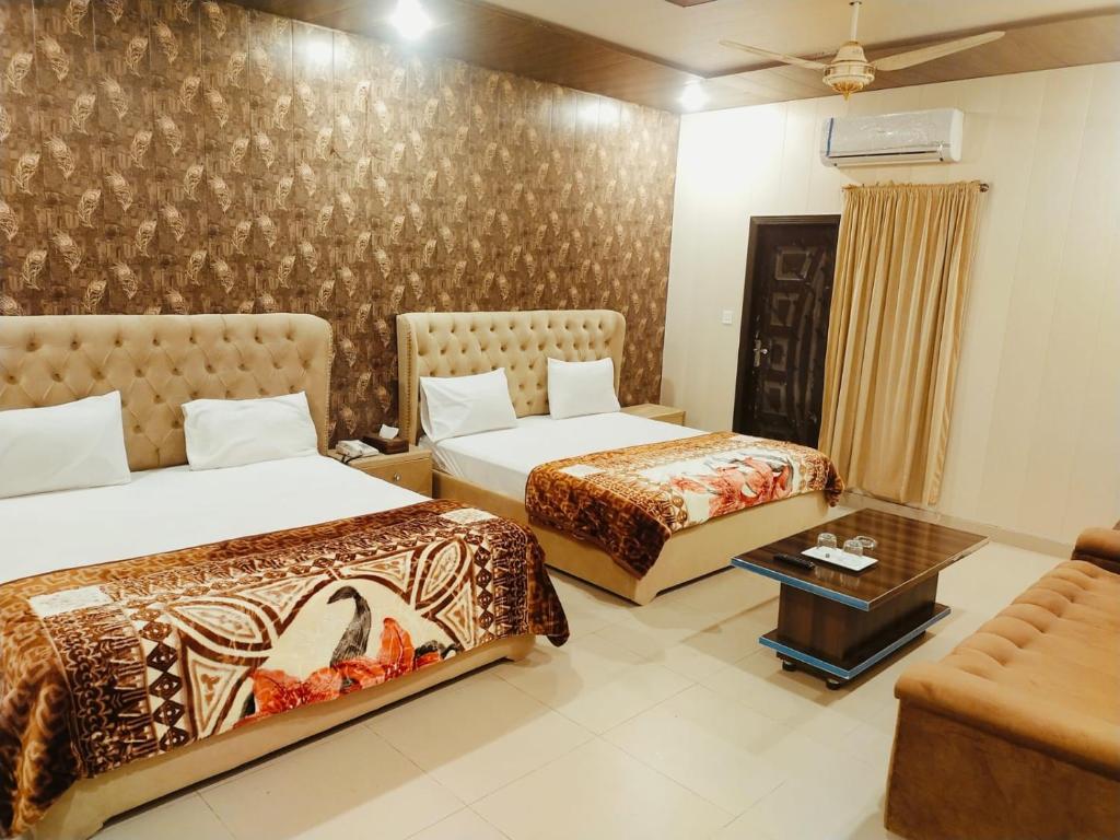 a hotel room with two beds and a couch at Royal Fort Executive Hotel Gulberg in Lahore