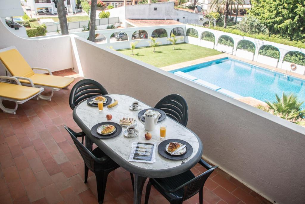 クアルテイラにある2 Bedroom Apartment in Quarteira with Balcony, Pool and Wi-Fi by Centralgarveのプール付きバルコニーにテーブルと食べ物