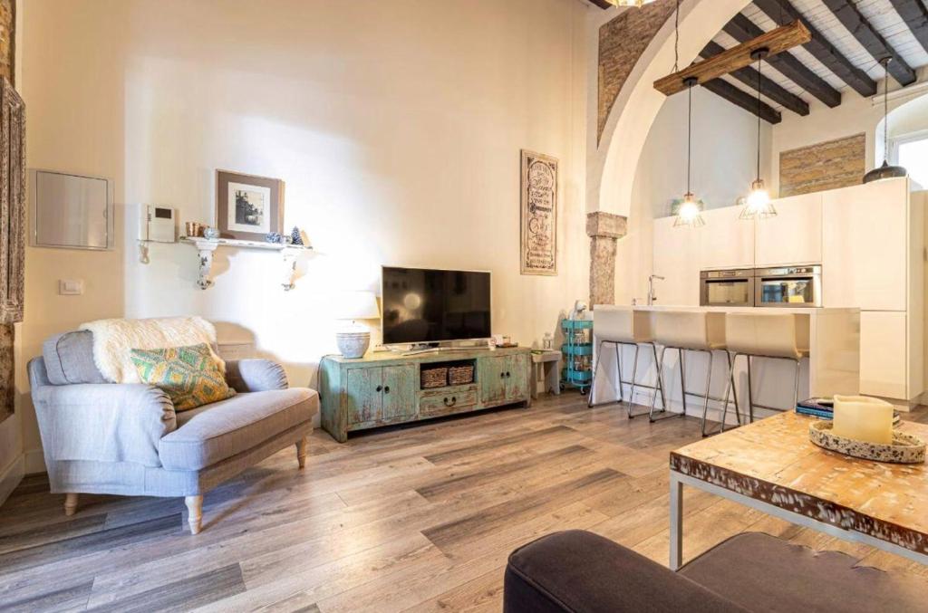 sala de estar con sofá, mesa y cocina en Loft Bodega San Blas con porche y parking, en Jerez de la Frontera