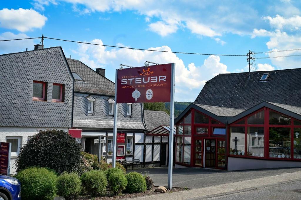 un panneau de rue devant un bâtiment dans l'établissement Hotel Steuer, à Allenbach