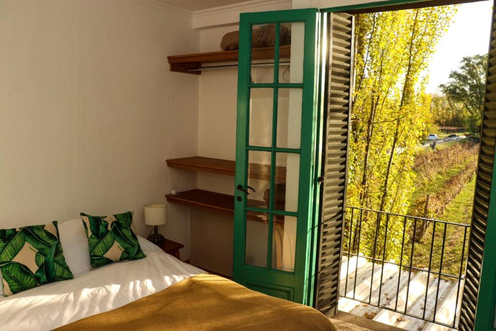 Habitación con puerta verde, cama y ventana en Bodega Trina Suites en Río Colorado