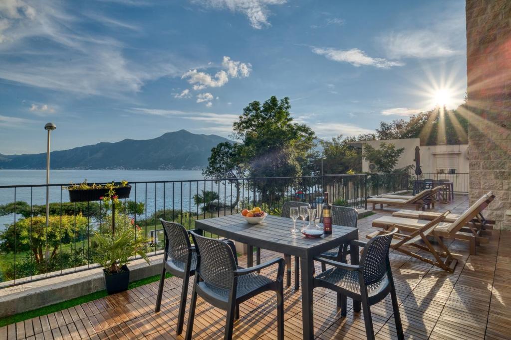 a deck with a table and chairs and a view of the water at Beachfront Villa Nautica in Kotor