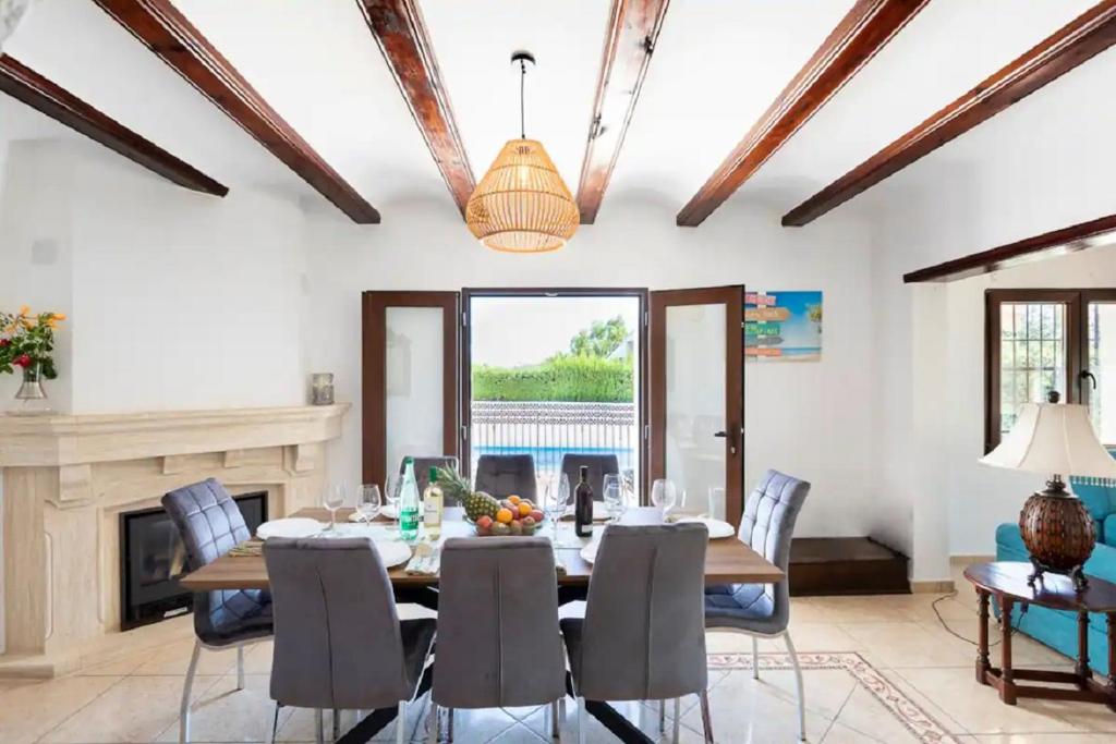 comedor con mesa, sillas y chimenea en Villa ISLANDIA SUPER CÓMODA, en Jávea