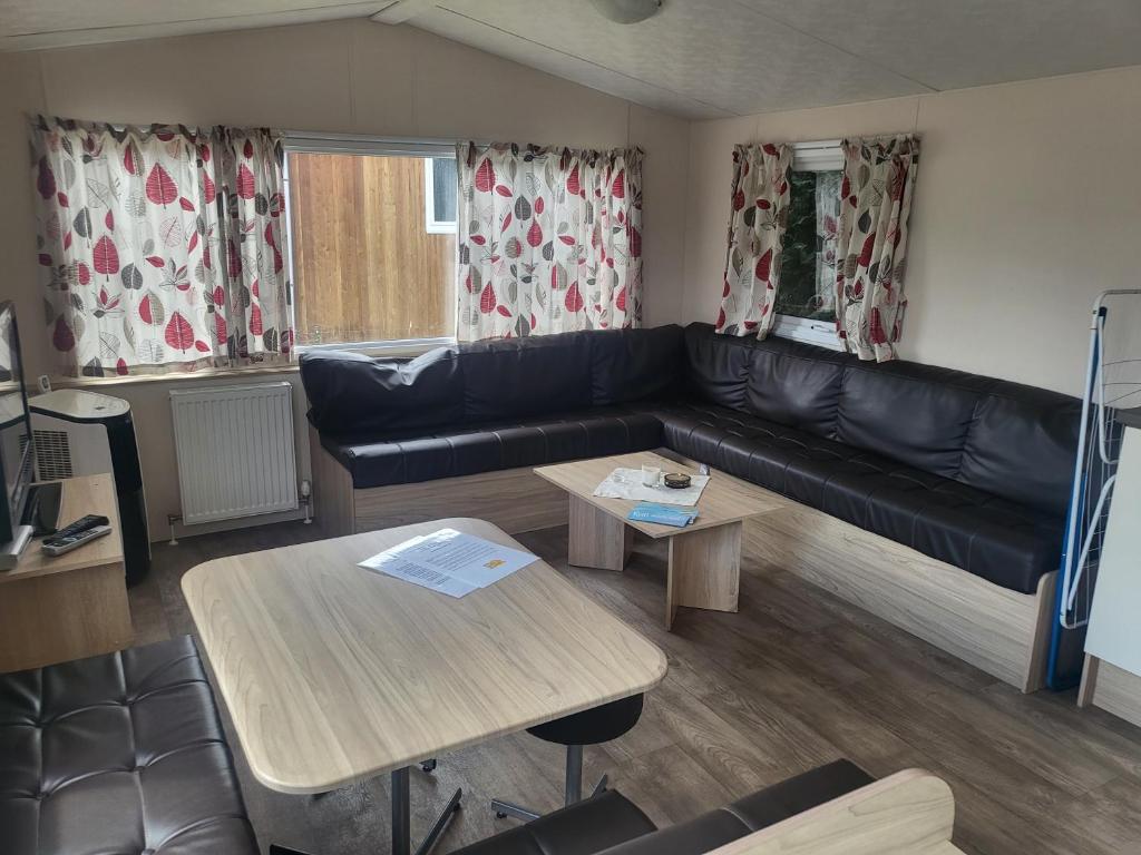 a living room with a black leather couch and tables at Märchencamping in Stuhr