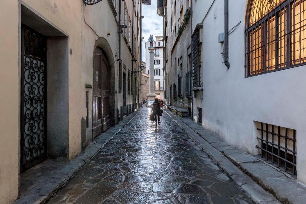 a person riding a bike down a cobblestone alley at numa I Fiore Apartments in Florence