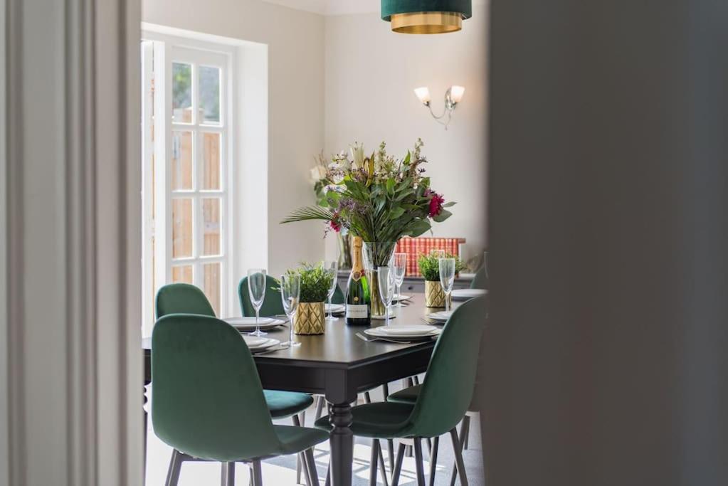a dining room with a table and green chairs at St George's - stylish family home in Sandwich in Kent
