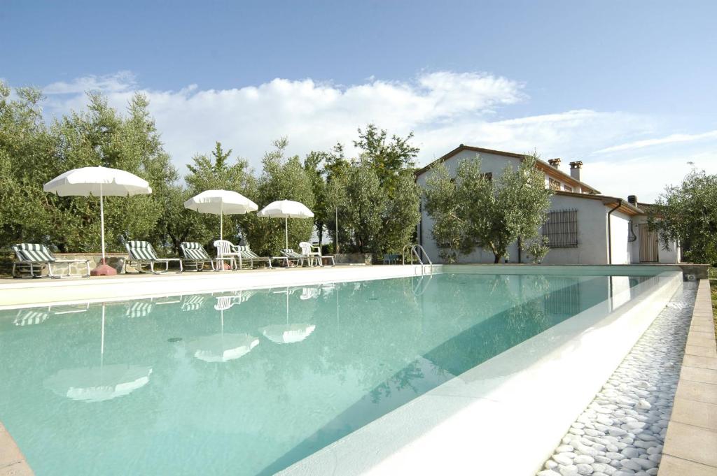 a swimming pool with chairs and umbrellas next to a house at Agriturismo Spazzavento in Vinci