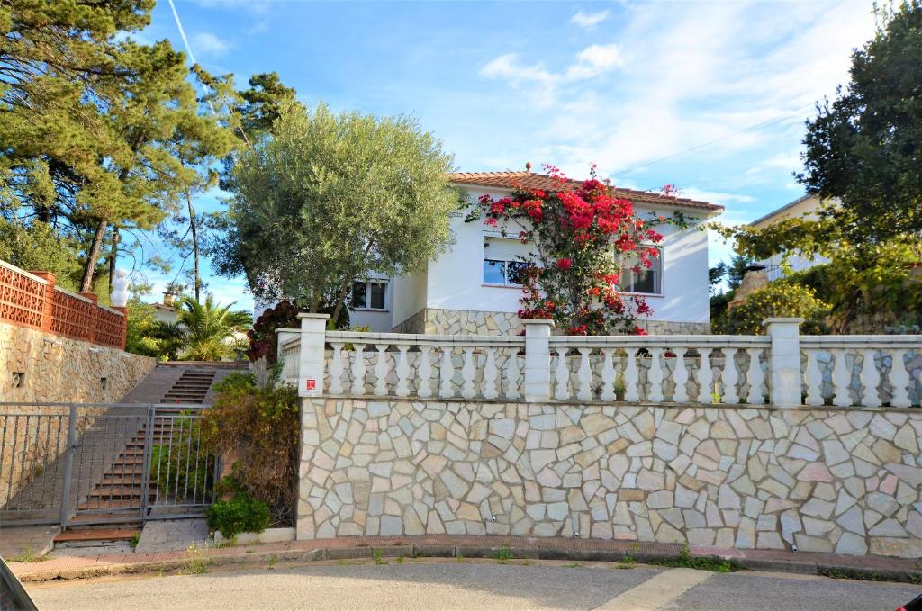 una casa blanca detrás de una valla de piedra con flores en Villa michelle, en Lloret de Mar