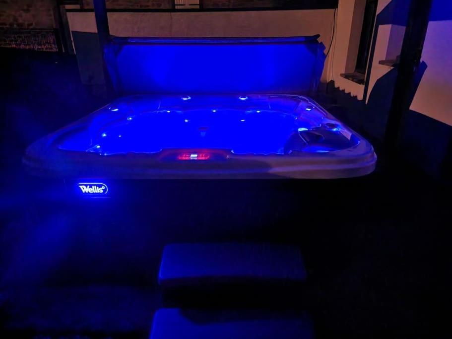 uma banheira azul num quarto escuro em Maison avec jacuzzi et sauna em Épinal