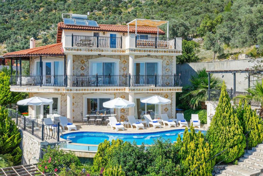 a large villa with a swimming pool and chairs at Villa Azalea in Kalkan