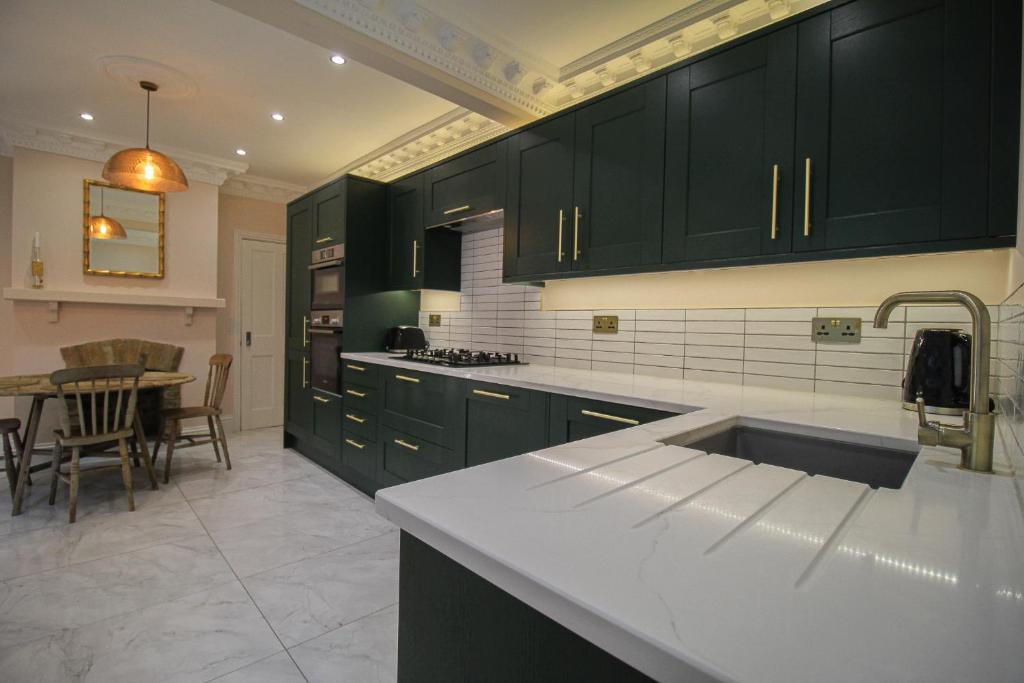 una cucina con armadi verdi scuri e tavolo di Milton Park - Serviced accommodation By Verano House a Portsmouth