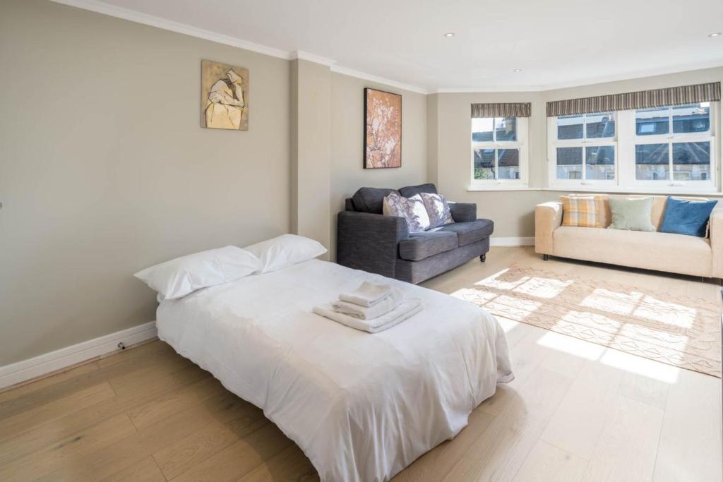 1 dormitorio con cama blanca y sofá en Elegant Modern 1 Bed Barons Court close to Tube sleeps Four en Londres