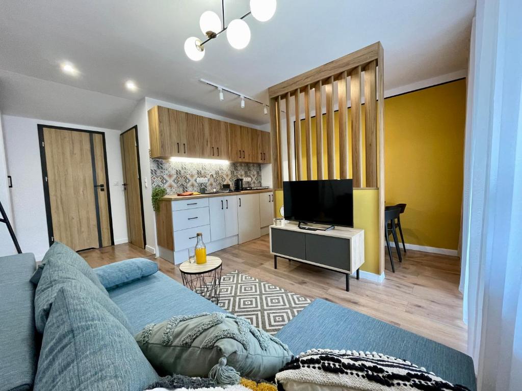 Il comprend un salon avec un canapé bleu et une cuisine. dans l'établissement Apartament za Ratuszem - z balkonem, à Radom
