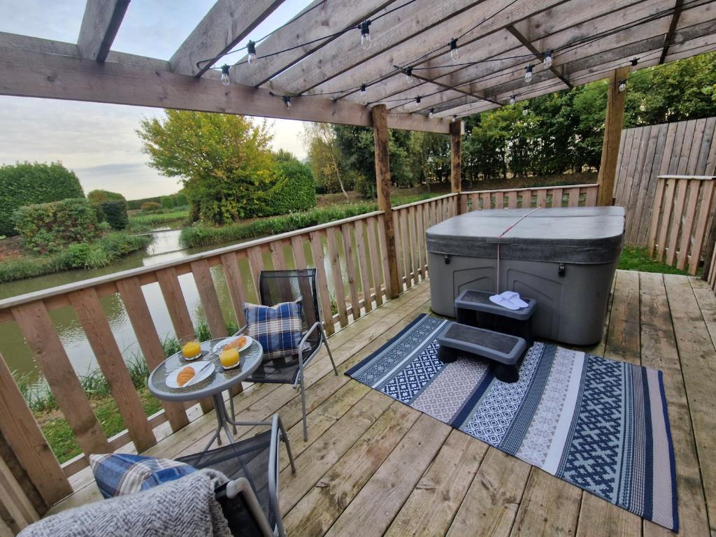 a deck with a grill and a table and chairs at Wren - Luxury Shepherd's Hut with Hot Tub in Manea
