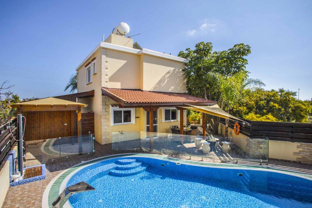 a house with a swimming pool in front of a house at Tropical Beach Villa in Ayia Napa