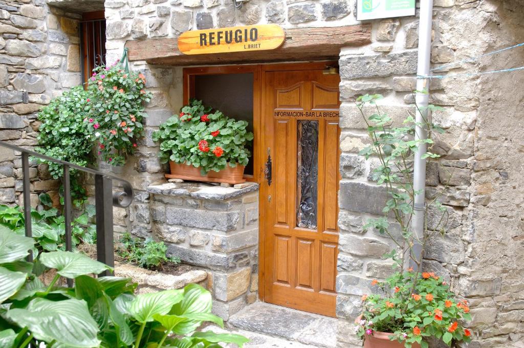 um edifício de pedra com uma porta de madeira e algumas plantas em Refugio Lucien Briet em Torla