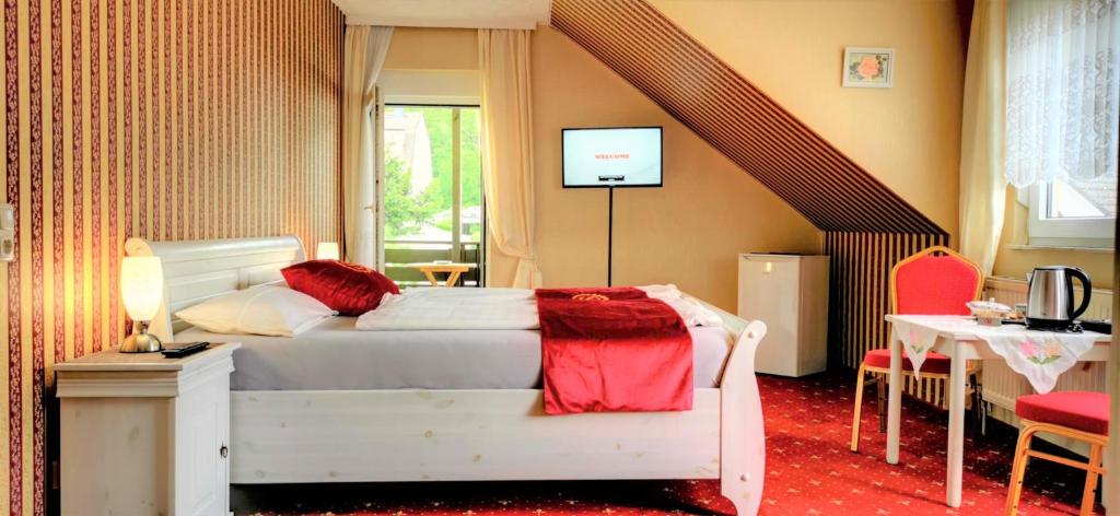 Schlafzimmer mit einem Bett, einem Tisch und einem TV in der Unterkunft Pension Tannenkopf - Hotel Garni in Bad Soden-Salmünster
