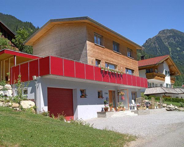 een groot huis met een rood dak op een heuvel bij Haus Barbara in Sankt Gallenkirch