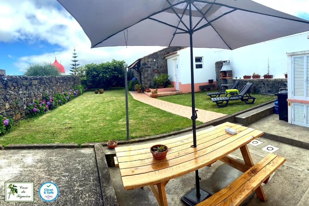 una mesa de picnic con una sombrilla en un patio en Alojamento CASA DA FIGUEIRA en Ponta Delgada