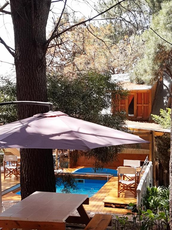 a white umbrella sitting next to a tree next to a pool at Cabanas Las Escondidas in Monte Hermoso