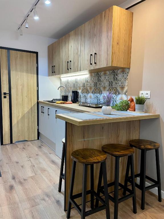 a kitchen with wooden cabinets and bar stools at Apartament w sercu miasta in Radom