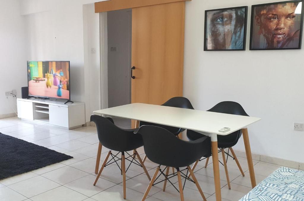 une salle à manger avec une table blanche et des chaises noires dans l'établissement ELLA LUXURY APARTMENT - (BREAKBOOKING CY), à Limassol