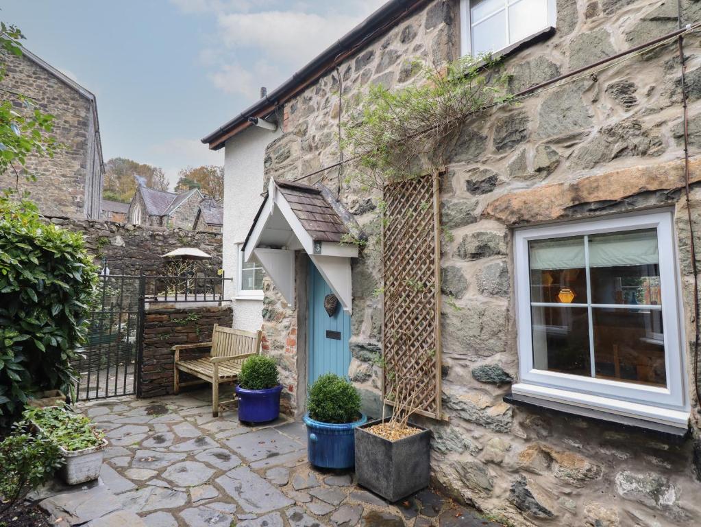 a stone house with a blue door and plants at 3 Ivy Court in Dolgellau