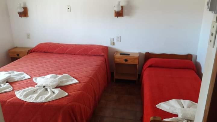Habitación de hotel con cama roja y silla en Grupo Idaho en Villa Gesell